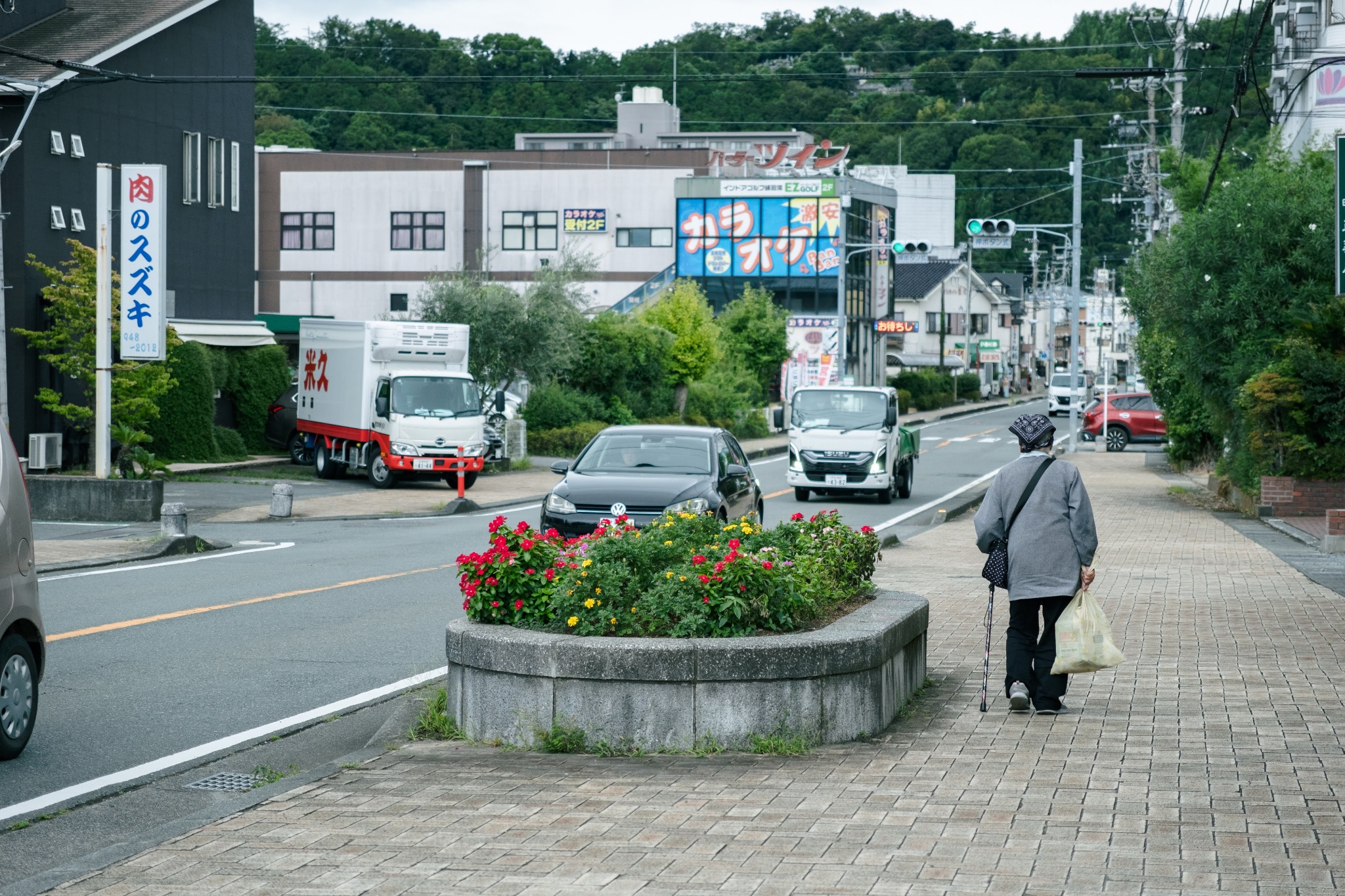 花壇の脇を一人歩く町の通り