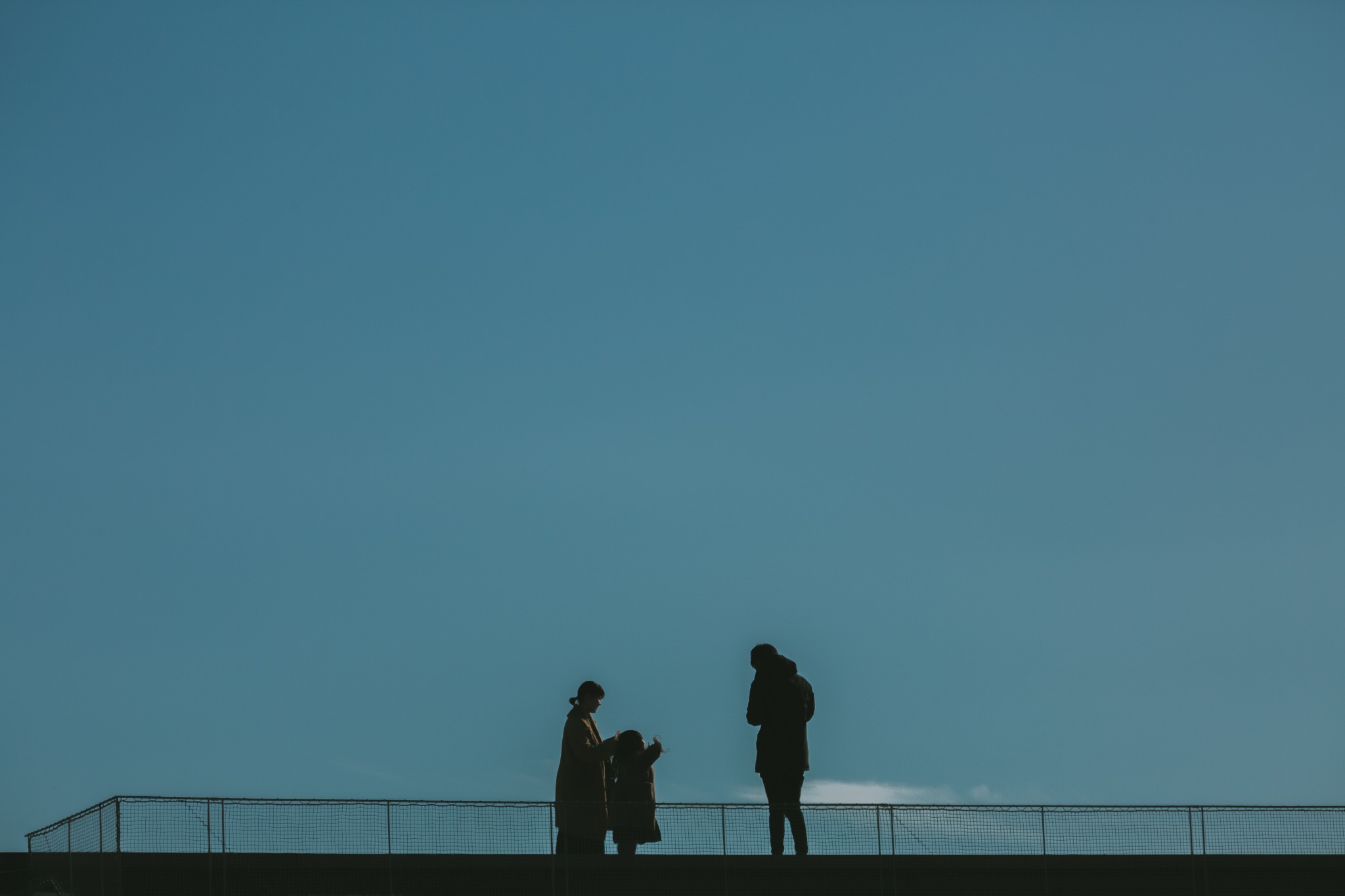 青い空の下で向き合う二人のシルエット