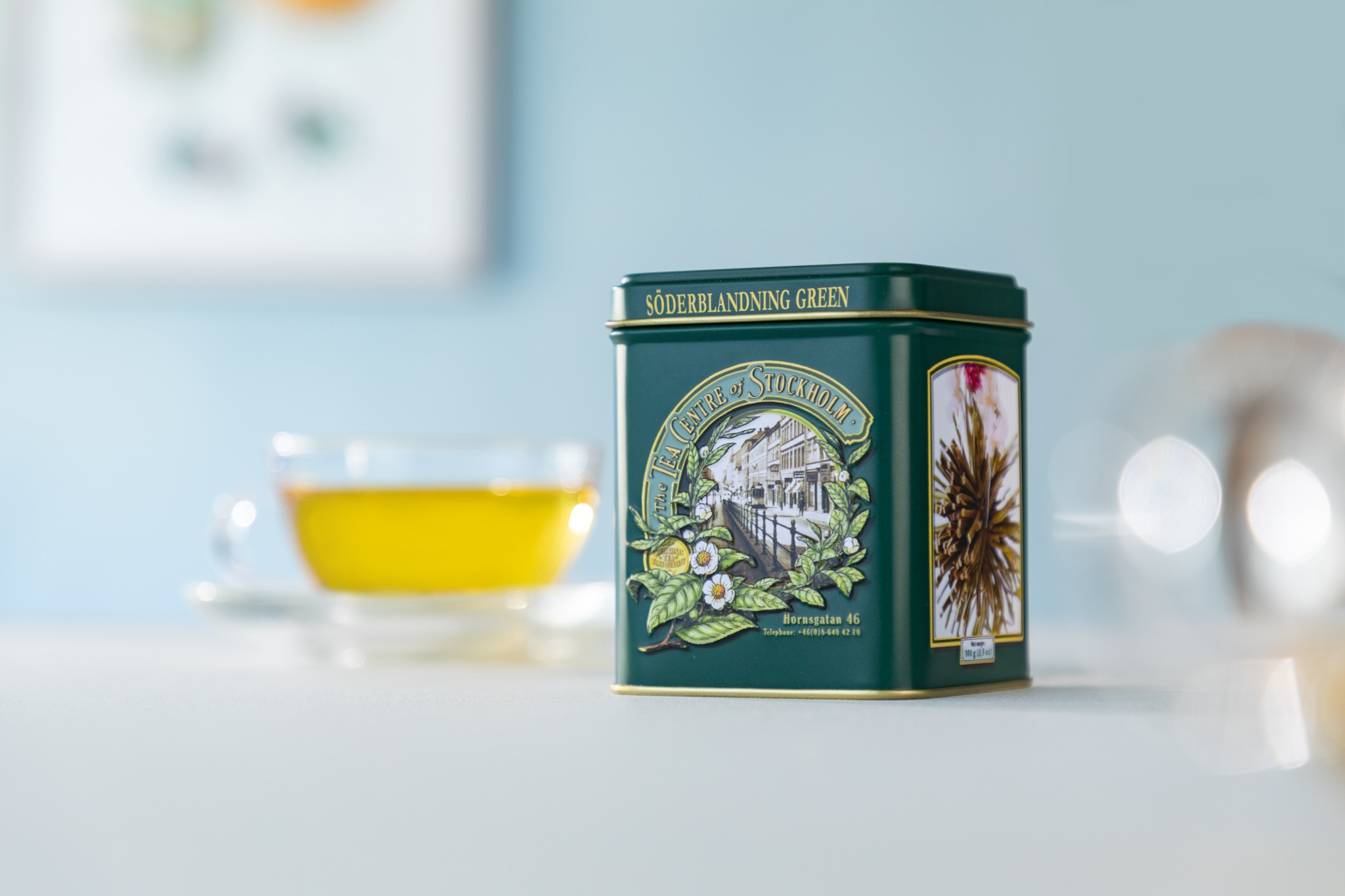 水色の背景で撮影した紅茶缶とティーカップ