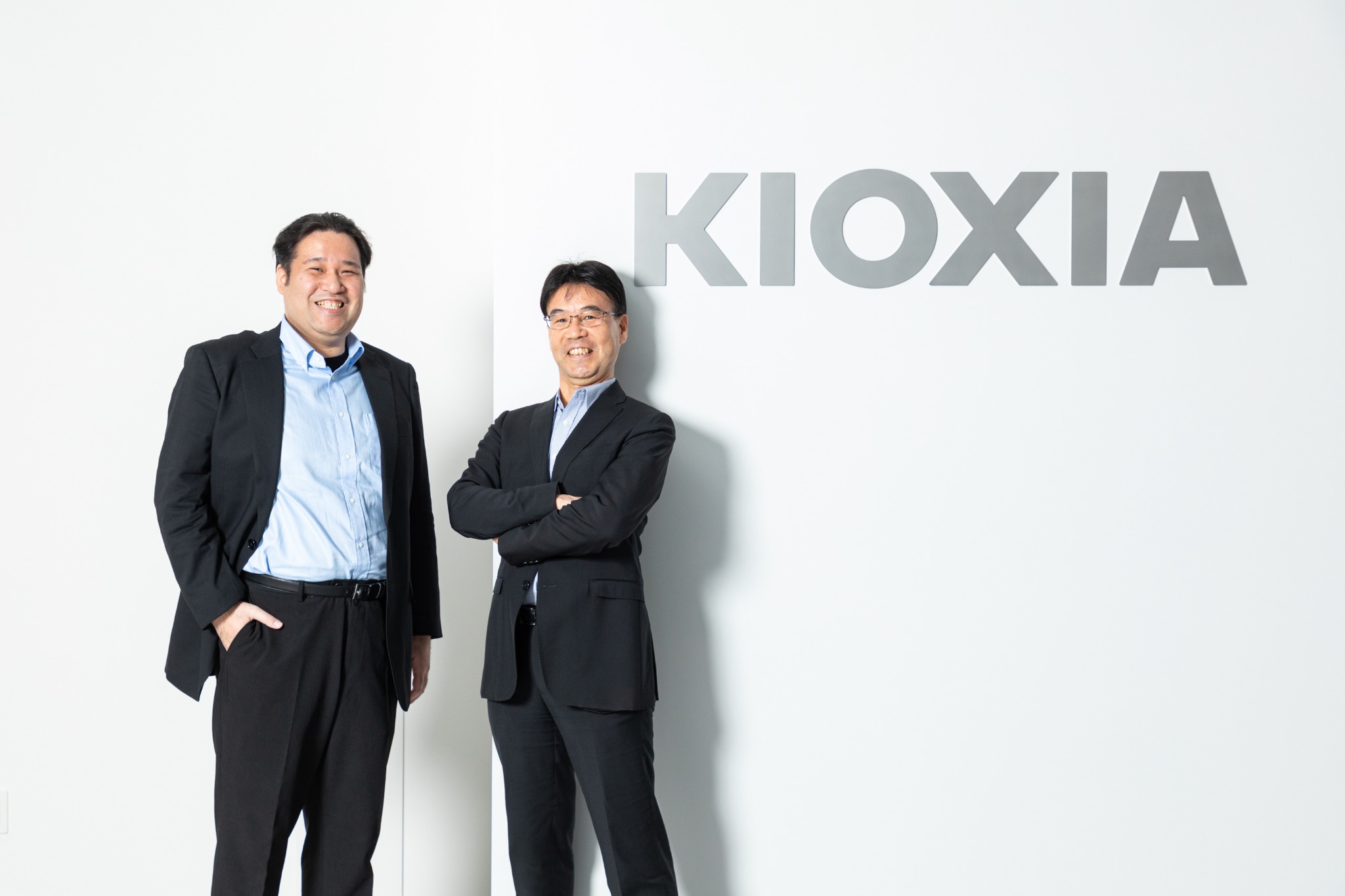 企業ロゴの前で撮影した二人の取材ポートレート