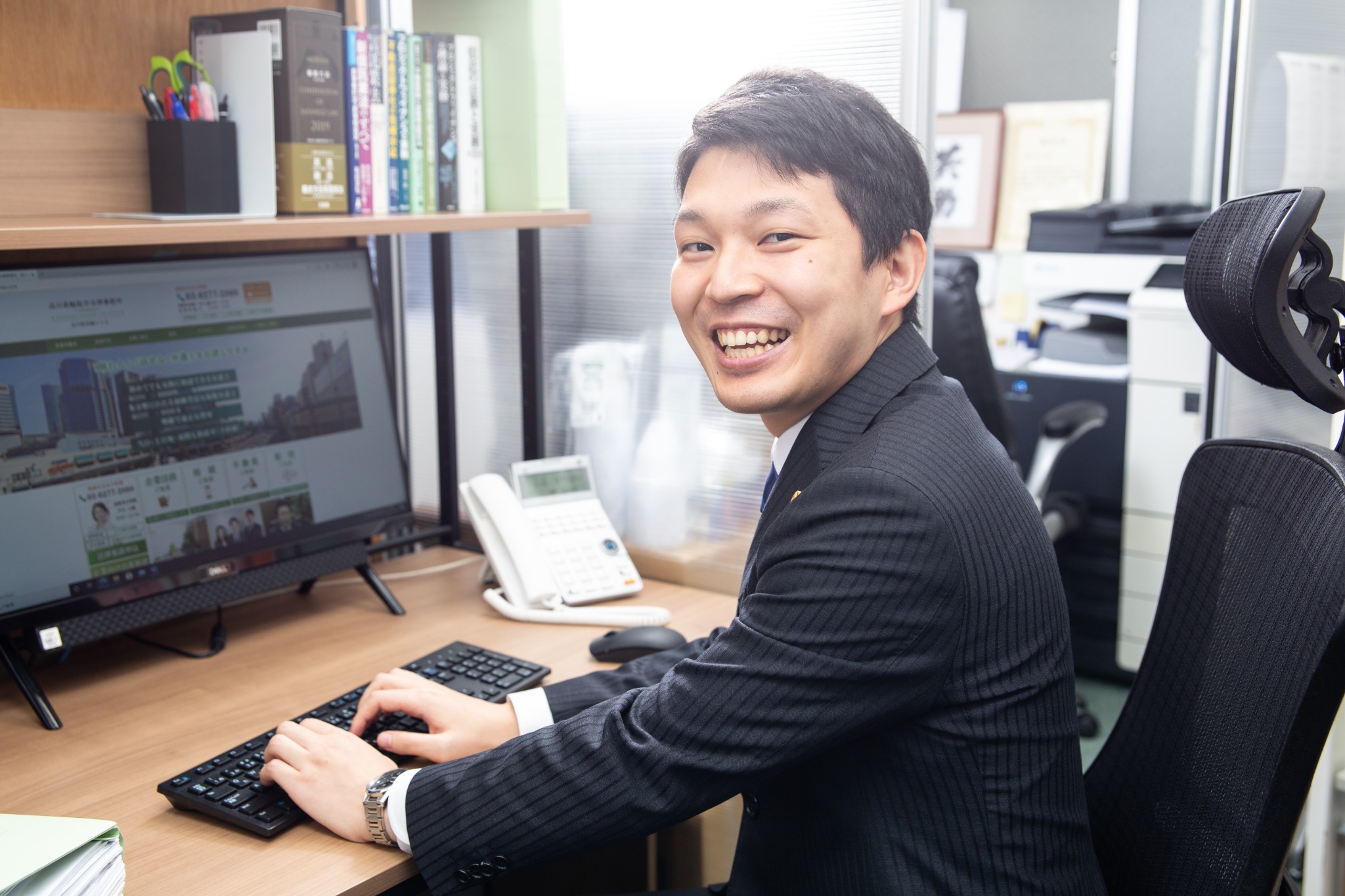 オフィスのデスクで働く社員の自然な笑顔