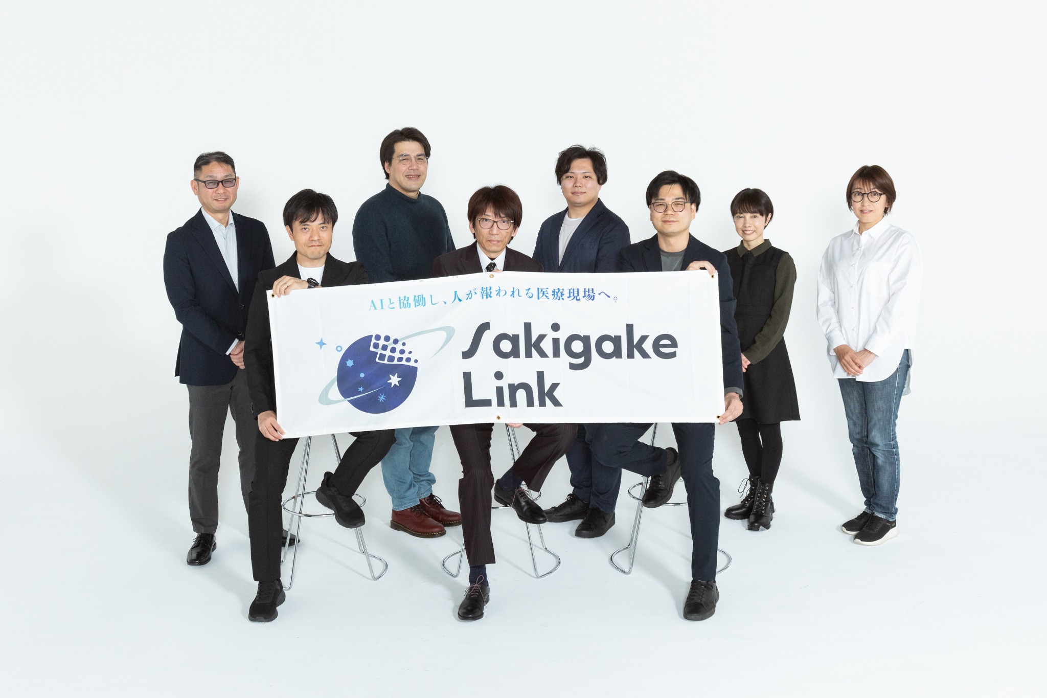 白いスタジオで企業プロジェクトのバナーを囲むチームポートレート